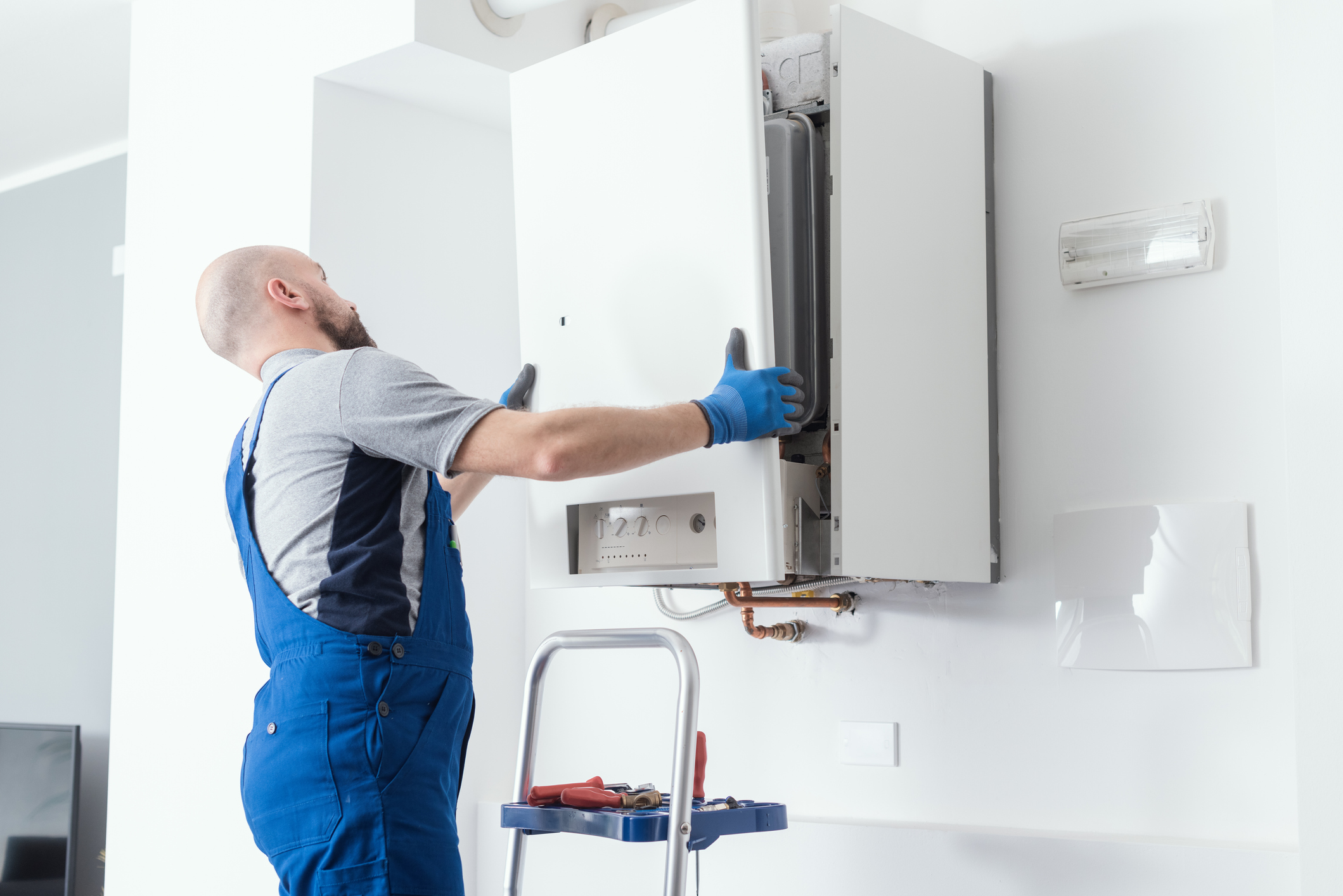 HVAC technician replacing the front panel of a boiler in a Michigan home