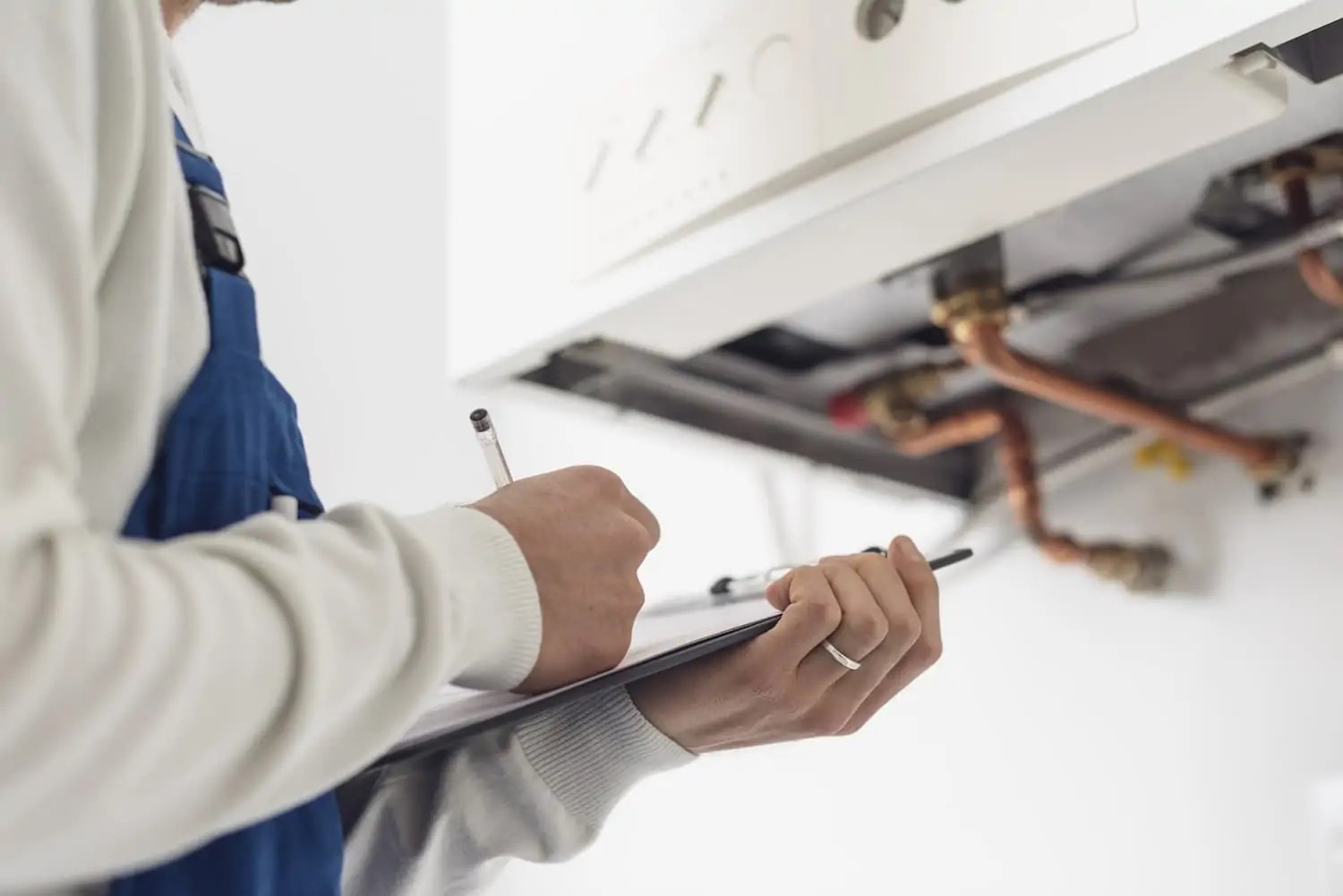 Technician standing in front of a boiler with a clipboard